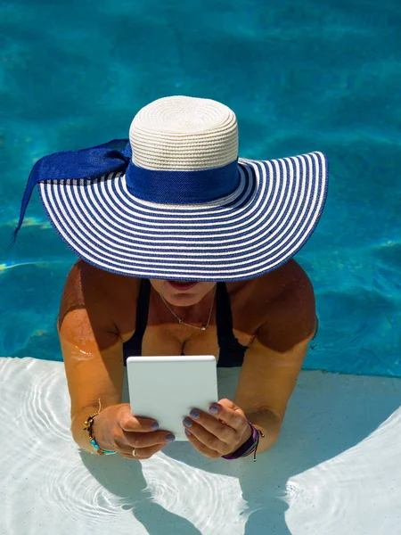 Woman at the swimming pool reading — Stock Photo, Image