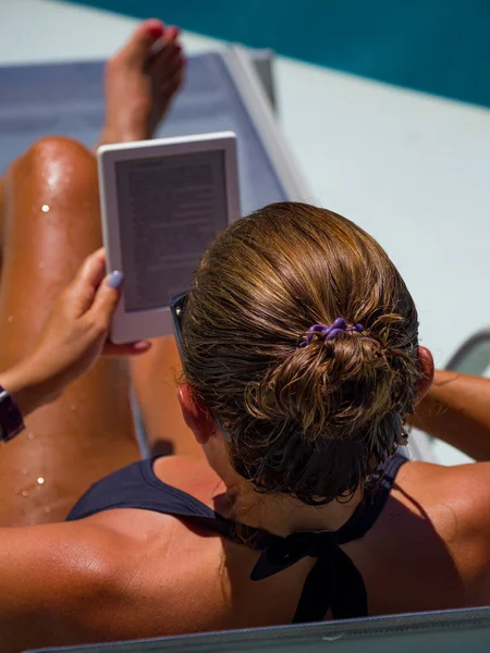 Egy nő a medencénél olvasott. Stock Kép