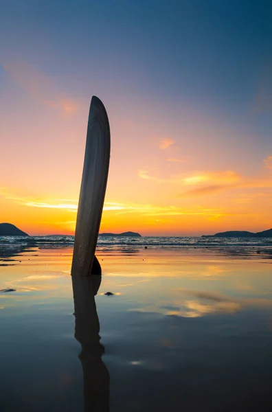 Tabla de surf en la playa en la orilla del mar al atardecer — Foto de Stock