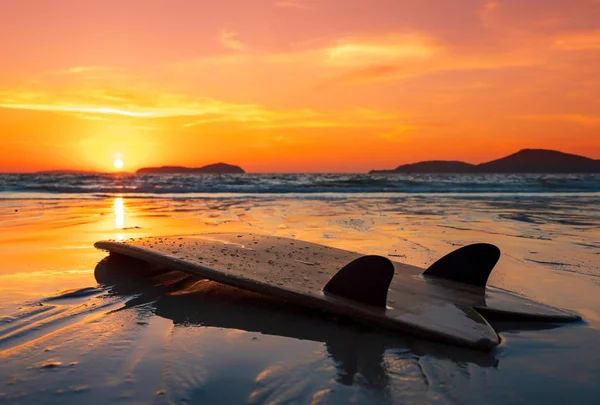 Planche de surf sur la plage au bord de la mer au coucher du soleil — Photo