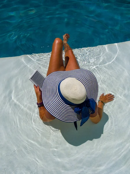 Woman at the swimming pool reading — Stockfoto