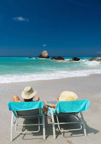 Casal em espreguiçadeiras relaxando na praia em Lefkada — Fotografia de Stock