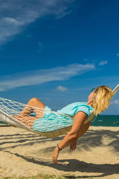 Vrouw zitten in een hangmat op het strand. — Stockfoto