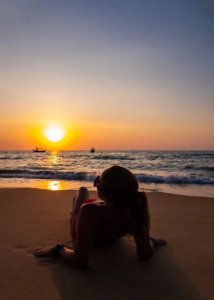 Femme assise sur la plage au coucher du soleil — Photo