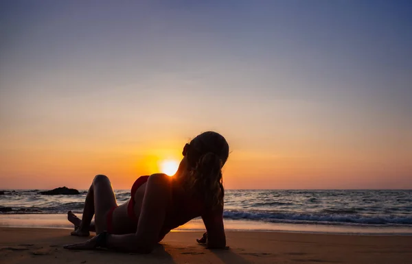 Žena sedící na pláži při západu slunce — Stock fotografie