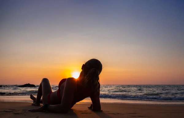 Vrouw zittend op het strand bij zonsondergang — Stockfoto