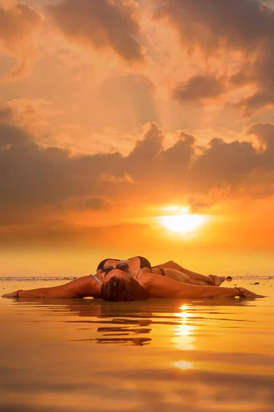 Silhueta de uma mulher jovem e apta na praia ao pôr do sol — Fotografia de Stock