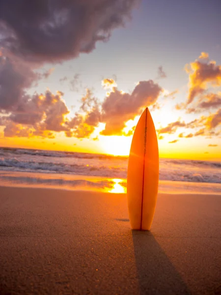 Tabla de surf en la playa en la orilla del mar al atardecer con bellísimo fu. — Foto de Stock
