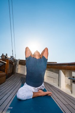 Yelkenli yatta yoga yapan bir adam.