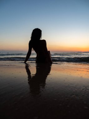 Kadın tropik plajda güneşleniyor.