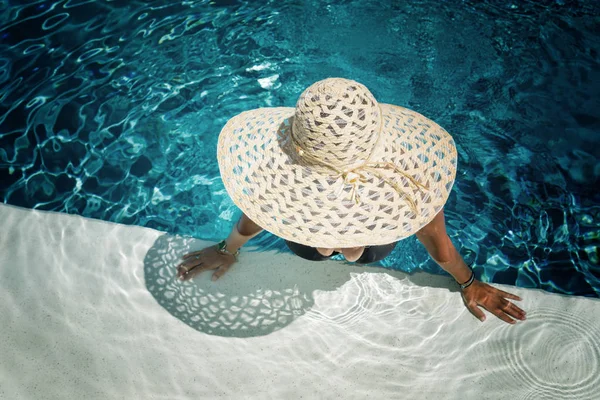 Mooie vrouw in een hoed genieten van een zwembad — Stockfoto