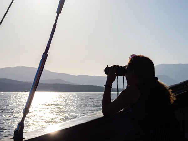 Woman looking at the sea through binocular