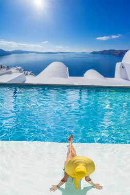 Havuzda dinlenen bir kadın ve Santorini Yunanistan manzarasına bakıyor