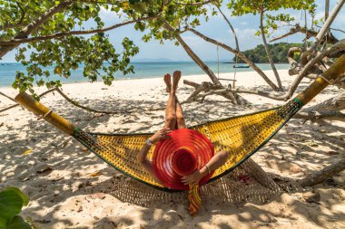 Kumsalda hamakta dinlenen bir kadın.