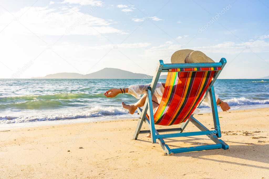 Woman sitting on a deck chair at the tropical beach