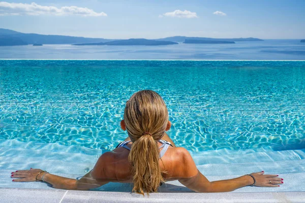 ギリシャのサントリーニ島のスイミングプールで女性カルデラを眺めながら — ストック写真