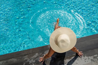Lüks içinde hasır şapkalı bir kadın. Yüzme havuzunun yanında beş yıldızlı bir spa merkezi.. 