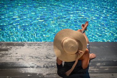 Kadın yüzme havuzunda güvertede oturuyor.