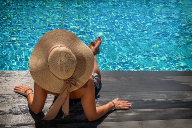 Kadın yüzme havuzunda güvertede oturuyor.