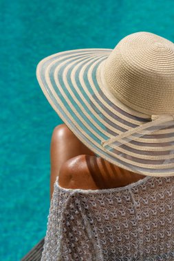 Lüks içinde hasır şapkalı bir kadın. Yüzme havuzunun yanında beş yıldızlı bir spa merkezi.. 