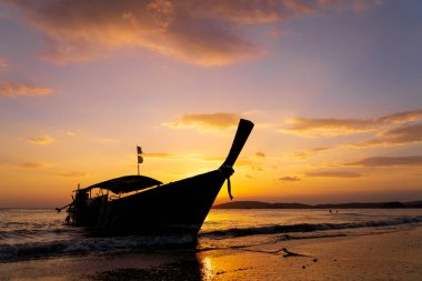 Geleneksel uzun kuyruklu tekne gün batımında Tayland sahilinde.