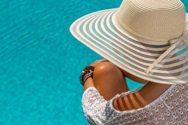Lüks içinde hasır şapkalı bir kadın. Yüzme havuzunun yanında beş yıldızlı bir spa merkezi.. 