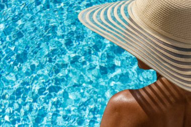 Lüks içinde hasır şapkalı bir kadın. Yüzme havuzunun yanında beş yıldızlı bir spa merkezi.. 