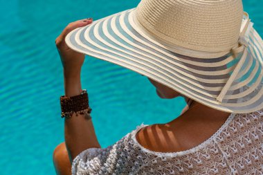 Lüks içinde hasır şapkalı bir kadın. Yüzme havuzunun yanında beş yıldızlı bir spa merkezi.. 