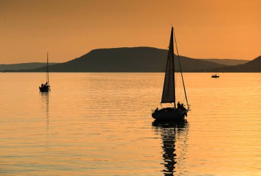 Gün batımında Balaton Gölü 'nde yelkenli.