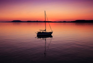 Gün batımında Balaton Gölü 'nde yelkenli.