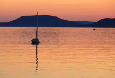 Gün batımında Balaton Gölü 'nde yelkenli.