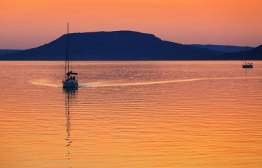 Gün batımında Balaton Gölü 'nde yelkenli.