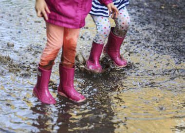 Playful child outdoor jump into puddle in boot after rain clipart