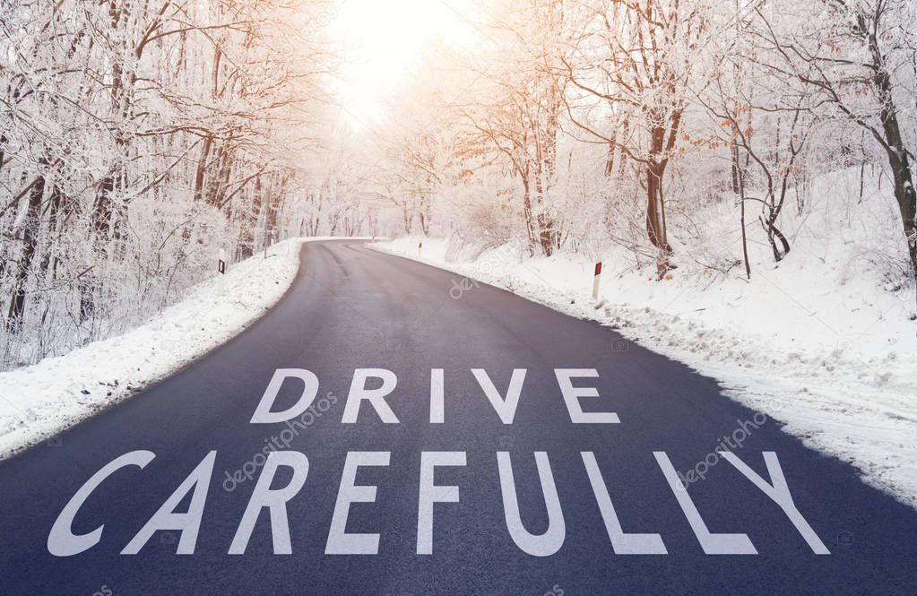 Empty road in forest in winter with drive carefully text