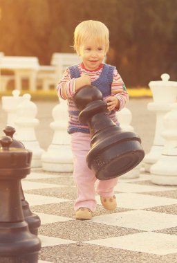 Dışarıda satranç figürleri olan bir çocuk.