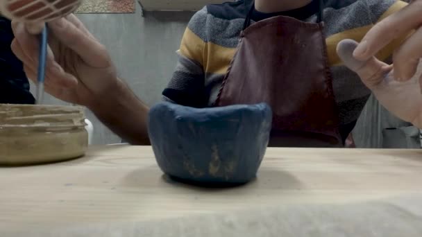 クローズ アップ ビュー コース職人で青と黄色の塗料で陶器の小さな紅茶バイアル作品をペイント ブラシで手をマンします — ストック動画