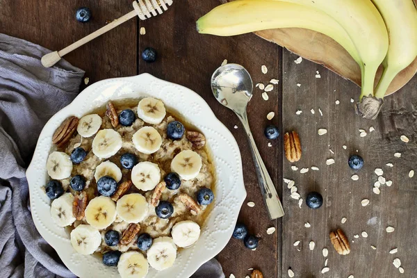 Hot Breakfast Healthy Oatmeal Pecans Bananas Blueberries Honey Rustic Background — Stock Photo, Image