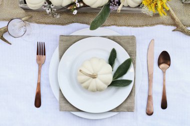 Ayrılmış Şükran günü veya Halloween yer ayarı ile mini beyaz kabaklar ayarla bir çiftlik evi masada, kuzu kulağı yaprakları, boynuzları ve sonbahar için çiçekler.