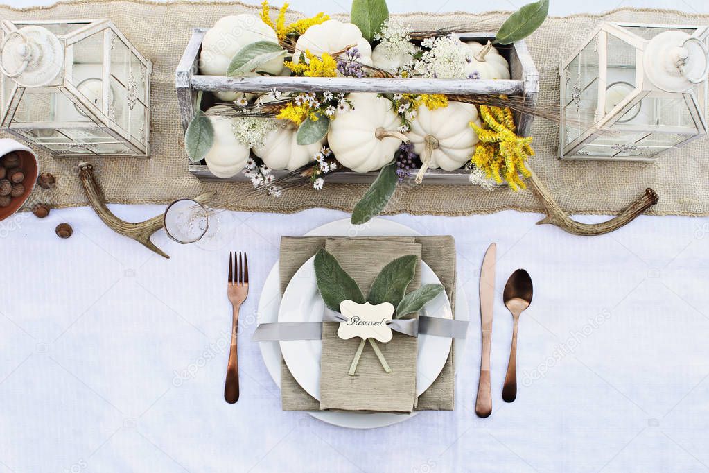 Reserved Thanksgiving or Halloween place setting at a farmhouse table set with mini white pumpkins, Lamb's Ears leaves,  antlers and wildflowers for autumn.