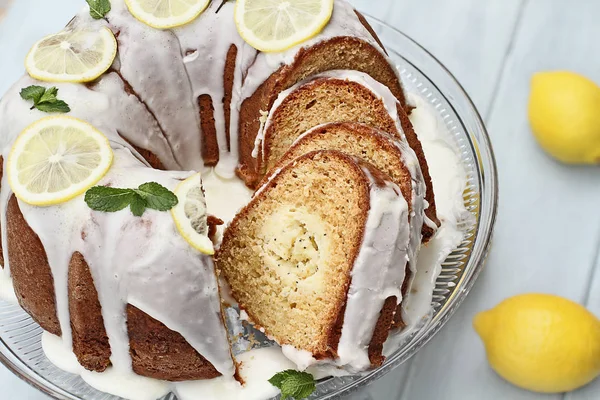 Above shot of lemon cream cheese bundt cake with cream cheese filling in the center cut into slices. Fresh lemons in background. Extreme shallow depth of field.