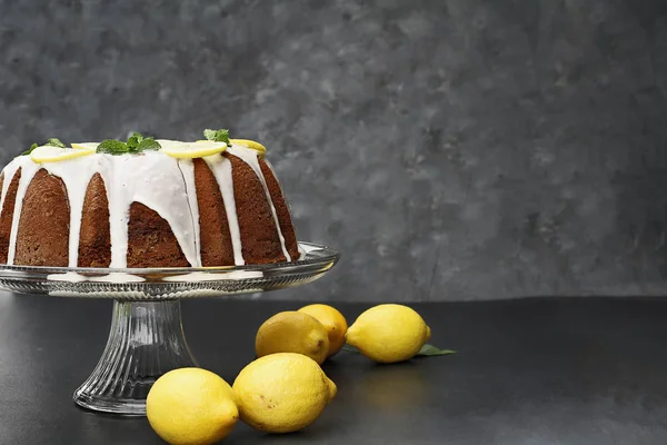 Whole lemon cream cheese bundt cake with slices of fresh lemons and mint on top. Extreme shallow depth of field with selective focus on cake. Free space for text.