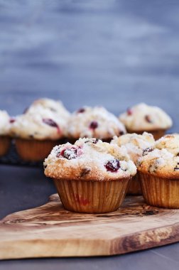 Yabanmersini Muffins limon şeker gevşek çilek ile bir rustik kesme tahtası üzerinde tepesi ile. Kek raf arka planda soğutma üzerinde. Muffin ön planda tarih seçici odak ile alan aşırı sığ derinliği.