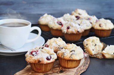 Daha fazla Fırıncılar rafına soğutma ile yabanmersini Muffins ağaç kesme tahtası. Alan seçici odak merkezi muffin aşırı sığ derinliği. Dumanı tüten fincan sıcak kahve içinde belgili tanımlık geçmiş.