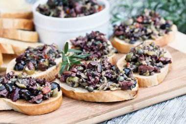 Ev yapımı karışık zeytin Tapenade yapılan sarımsak, kapari, zeytin yağı, Kalamata, siyah ve yeşil zeytin kızarmış ekmek üzerine yayıldı. Alan seçici odak merkezi kanepe üzerinde ile aşırı sığ derinliği.