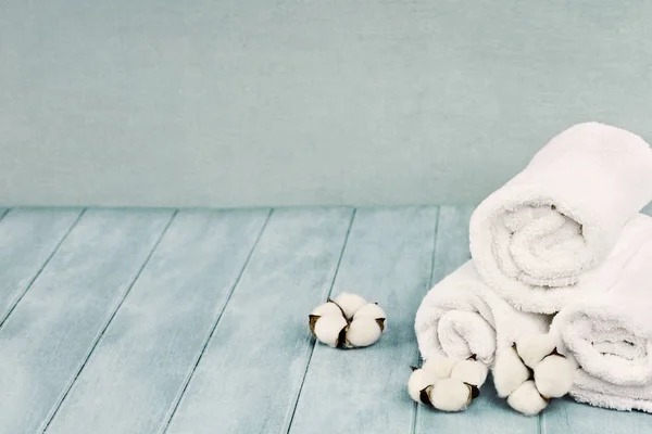 Zusammengerollte Weiße Flauschige Handtücher Mit Baumwollblumen Vor Unscharfem Blauem Hintergrund — Stockfoto