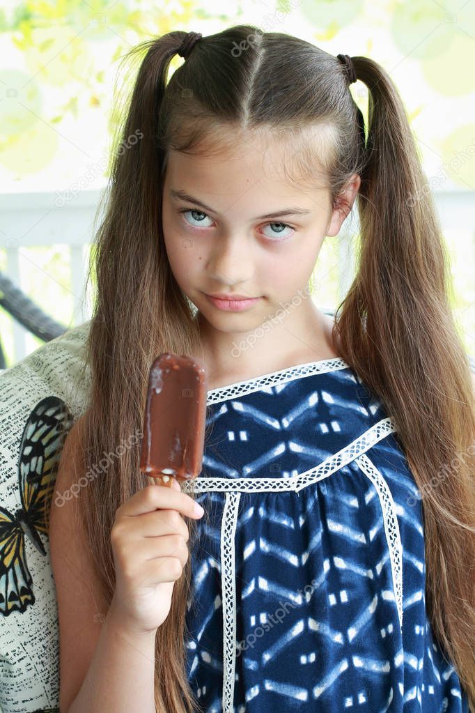 Young girl / child about to eat a chocolate ice cream on a stick. 