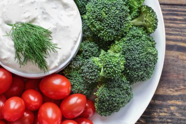 Ev yapımı ayran çiftlik salata sosu ile dereotu bir rustik ahşap arka plan üzerinde taze kiraz domates ve brokoli ile görev yaptı. Yukarıda üst görünümden görüntü.
