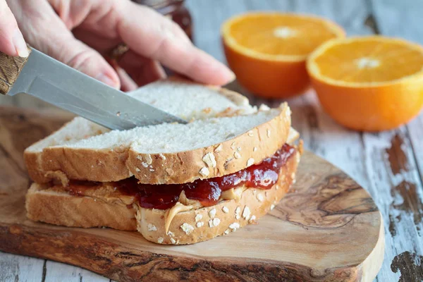 Kvinnans Hand Skära Jordnötssmör Och Gelé Smörgås Rustik Trä Skärbräda — Stockfoto