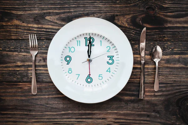 12小时间歇性禁食时间的概念与时钟在板上在质朴的木制桌子 顶视图 — 图库照片
