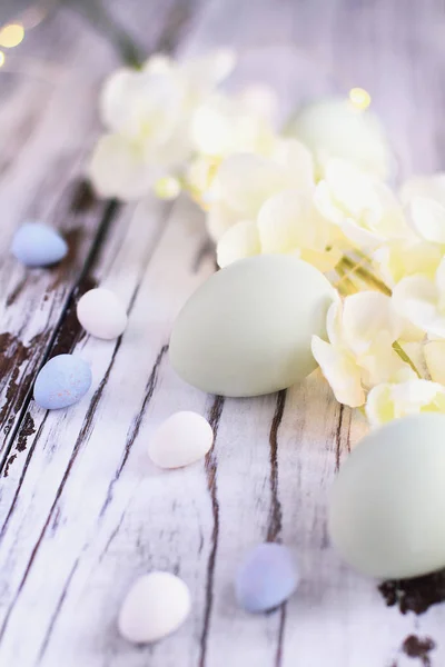 Uova di Pasqua uova di malto caramelle e fiori sullo sfondo di legno — Foto Stock